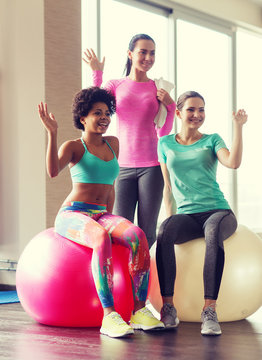 group of smiling women with exercise balls in gym