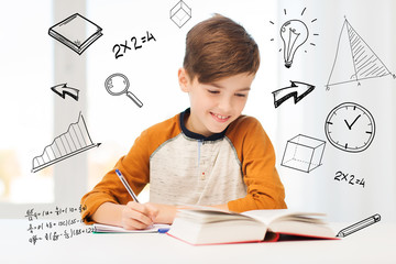 smiling student boy writing to notebook at home