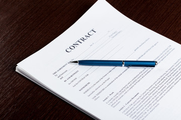 Pen and contract papers on wooden desk