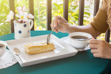 Women hand catching tea spoon cutting pie with black coffee on t