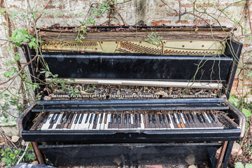 old piano with concrete wall and leaf
