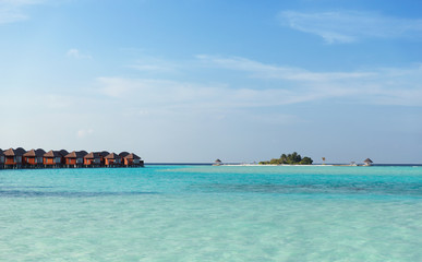 bungalow huts in sea water on exotic resort beach