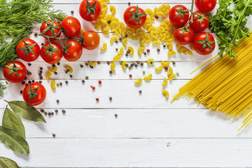 Naklejka na ściany i meble Background with pasta, tomatoes cherry and herb on white wooden