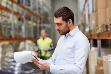 businessman writing to clipboard at warehouse