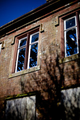 Derelict sandstone building with broken windows and boarded up d