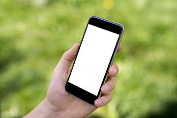 Hand holding black smartphone with blank screen against blurred grass background