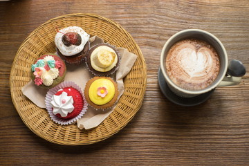 Cupcakes with hot chocolate on old wooden table.