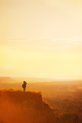 Obraz na płótnie Canvas Boy with tourist on a cliff at sunset