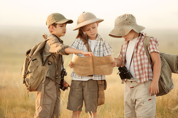 Group of kids travelers read a map at sunset