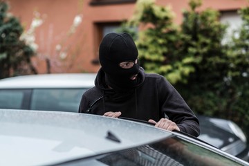 Car thief entering the vehicle and stealing a car.
