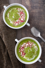 Pea cream with radishes on a rustic wooden background
