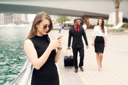 Business woman typing message while business couple walking in background.