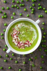 Pea cream with radishes on a rustic wooden background
