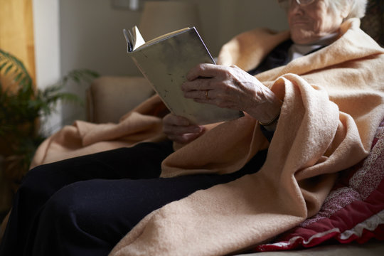 Senior woman reading book while sitting on sofa