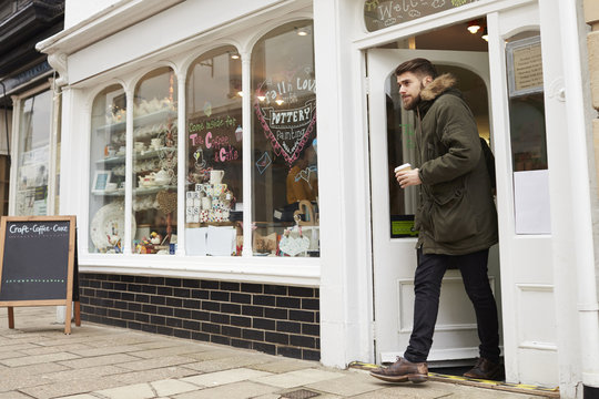 Male Customer Coming Out Of Cafe With Takeaway Coffee