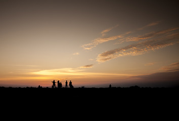 Obraz na płótnie Canvas man and woman photographer taking photo on sunset mountain peak
