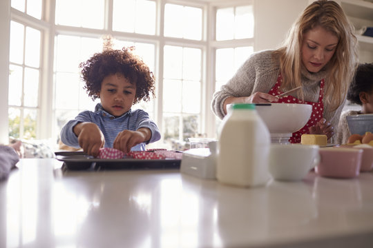 Mother Baking Cake With Children In Kitchen At Home