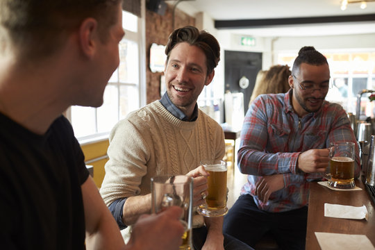 Three Male Friends Enjoying Drink In Bar