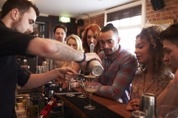 Bartender Giving Cocktail Making Lesson to Friends In Bar