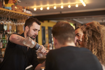 Bartender Giving Cocktail Making Lesson to Friends In Bar