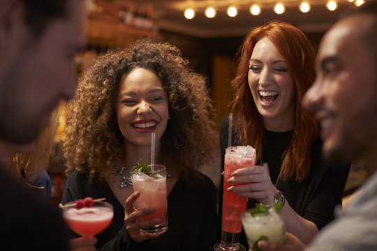 Group Of Friends Meeting For Evening Drinks In Cocktail Bar
