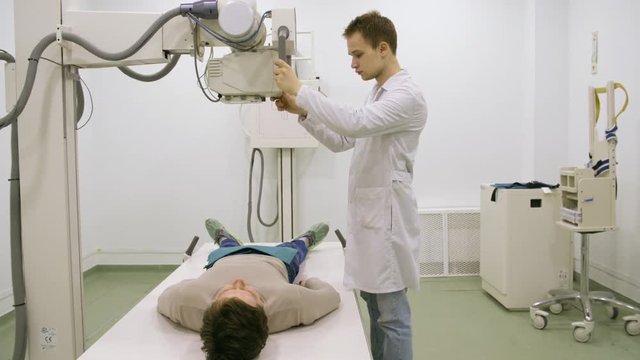 Young male doctor using xray machine to examine patient