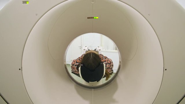 Unrecognizable woman with dark hair moving while lying inside mri