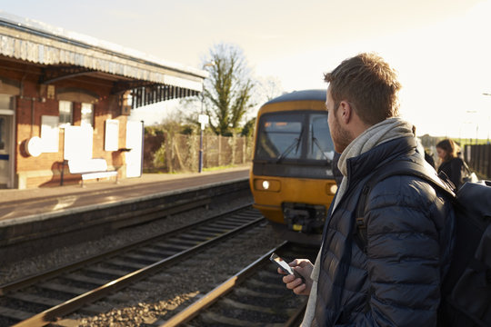 Man Standing On Railway Platform Waiting For Train To Arrive