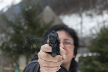 Frau schützt sich mit Pistole, bereit zur Selbstverteidigung. Fokus auf die rauchende Pistole.
