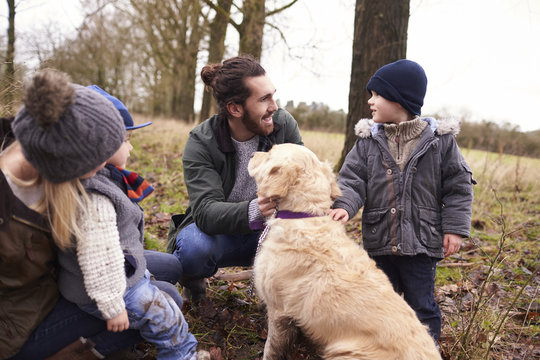 Family With Dog On Winter Walk Playing In Countryside