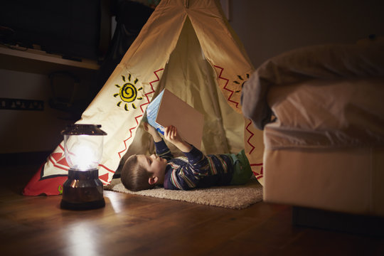 Young Boy Reading Inside Tent Set Up Indoors