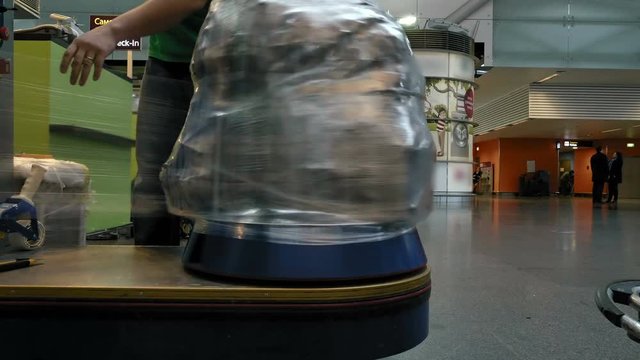 Wrapping luggage baggage bag at the airport terminal for security reason and safety protection from damage. 4K UHD video footage.