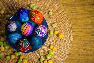 Blue plate with multicolored easter eggs, candies, straw background