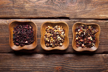Mix of dried tea leaves in the three bowl on wooden planks