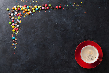 Colorful candies and coffee cup on stone background