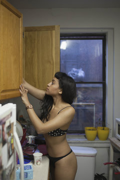 Young woman looking in her kitchen cupboards