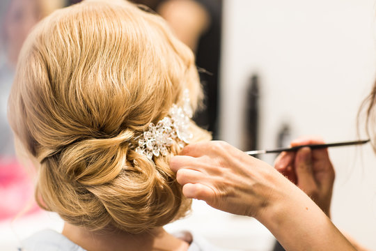 Hair stylist makes the bride before a wedding