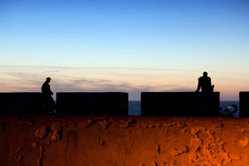 Silhouettes of unidentified tourists in Essaouira Fortress at sunset, Morocco