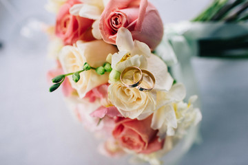 Obraz premium Wedding rings on a bouquet of roses