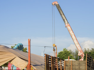 Red truck crane boom with hooks and scale weight above blue sky