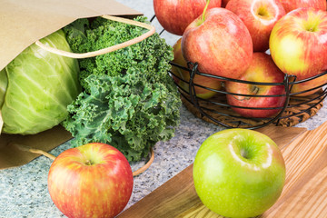 Farm organic apples, kale and green cabbage on a kitchen table.