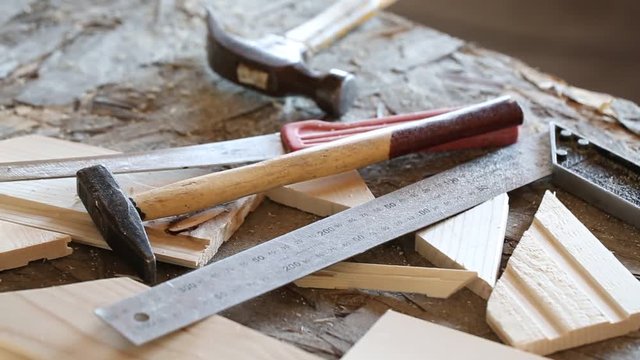 Hammer, knife, ruler and tongue and groove boards on working place, closeup
