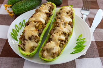 Baked stuffed zucchini, and vegetables on a white plate close up. Dietary lunch.