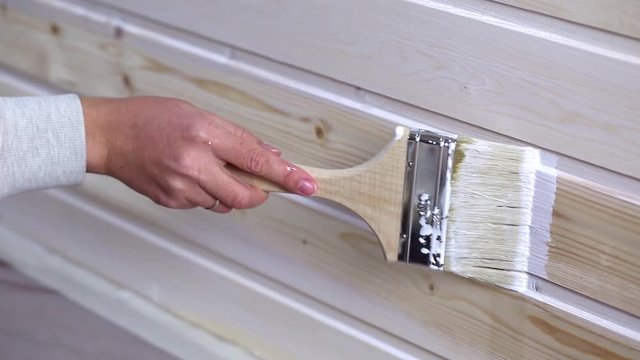 Woman painting wooden slot and key boards in white color with brush
