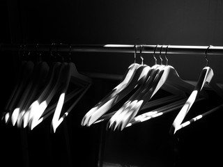 Kleiderbügel auf einer Kleiderstange im Dunkel bei Sonnenschein in einer alten Fabrik im Stadtteil...