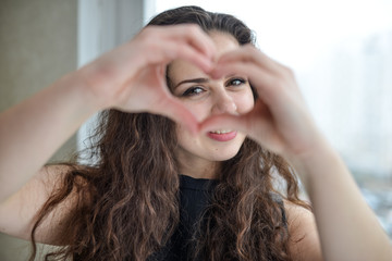 Beautiful young woman doing a heart shape with her hands