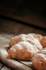 Fresh croissants, sprinkled with powdered sugar, vintage wooden