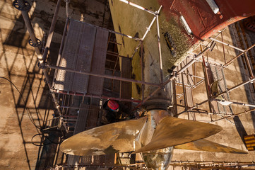 Dock worker repair propeller on a ship.