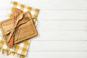 Wooden spoons and other cooking tools with napkins on the kitchen table.