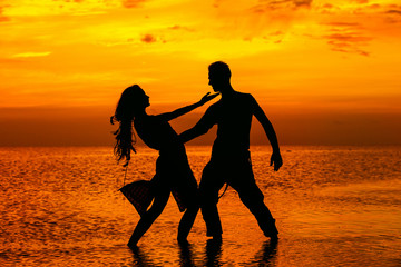 Silhoette of hot dancing couple at golden tropical sea sunset 